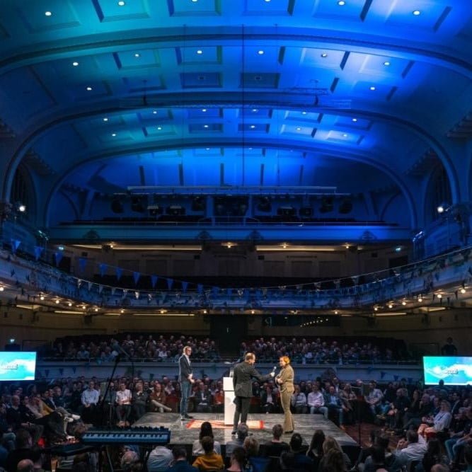 Overzichtsfoto van grote zaal met publiek tijdens de kick-off.