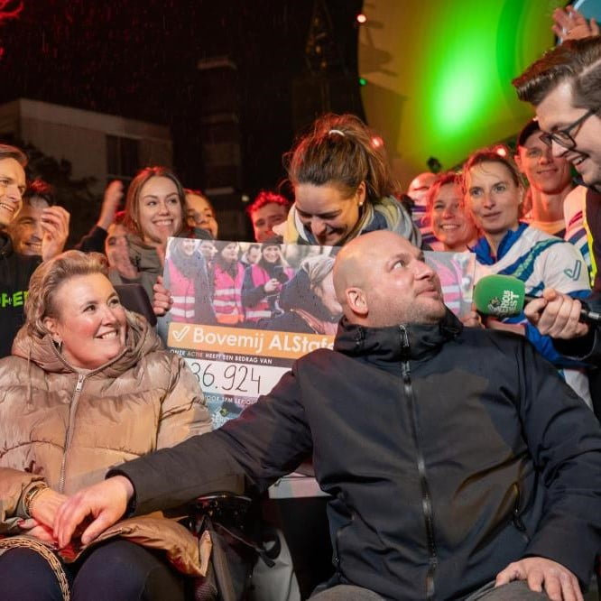 Foto van collega Joost en zijn vrouw Rheza met op de achtergrond de collega's die hebben hardgelopen.
