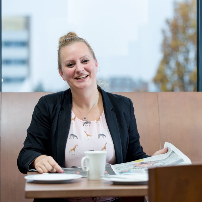 Dominique kijkt op van het lezen van de krant.