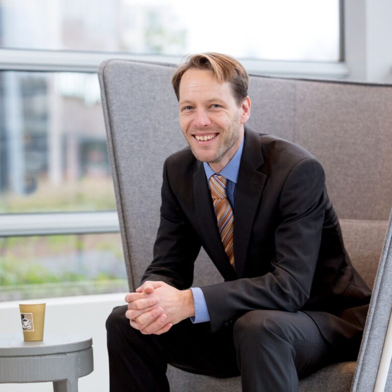 Jasper de Jong zittend op een stoel met een kop koffie