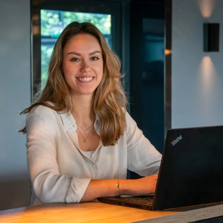 Foto van Marleen Gijsbers achter haar laptop.