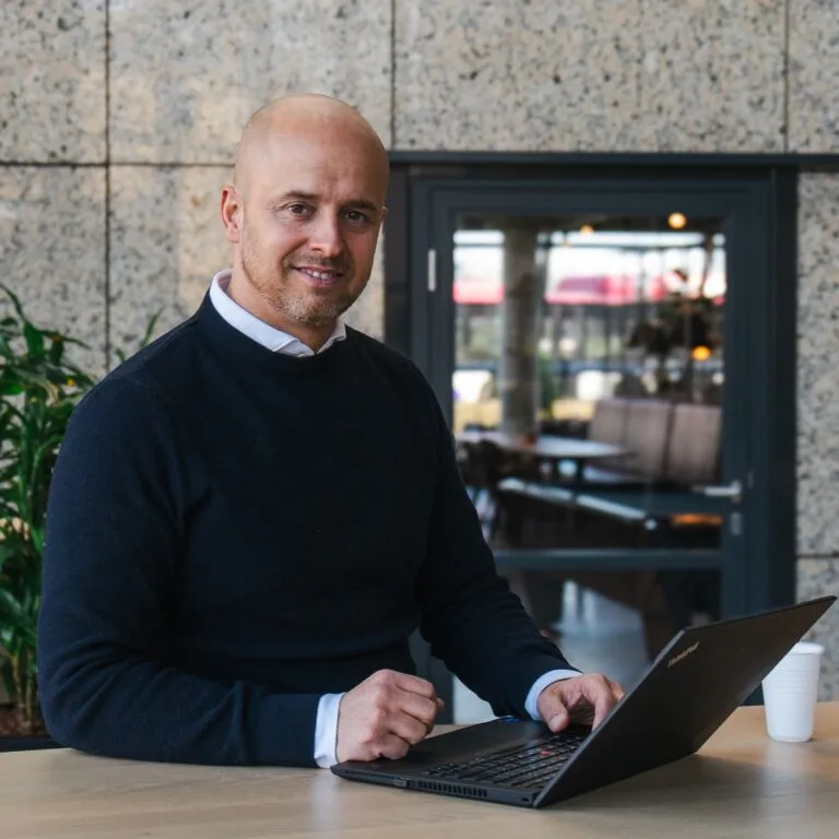 Foto van Raymond Ros achter zijn laptop.